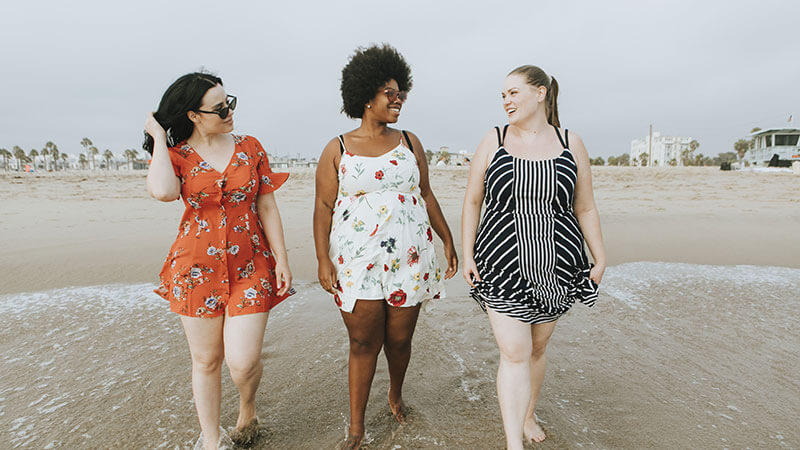 three bariatric patients talk happily on beach about upcoming weight loss surgeries