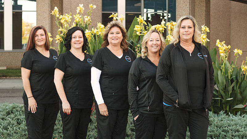 kc bariatric case managers smile at camera in front of flowers outside of The Bariatric Center of Kansas City
