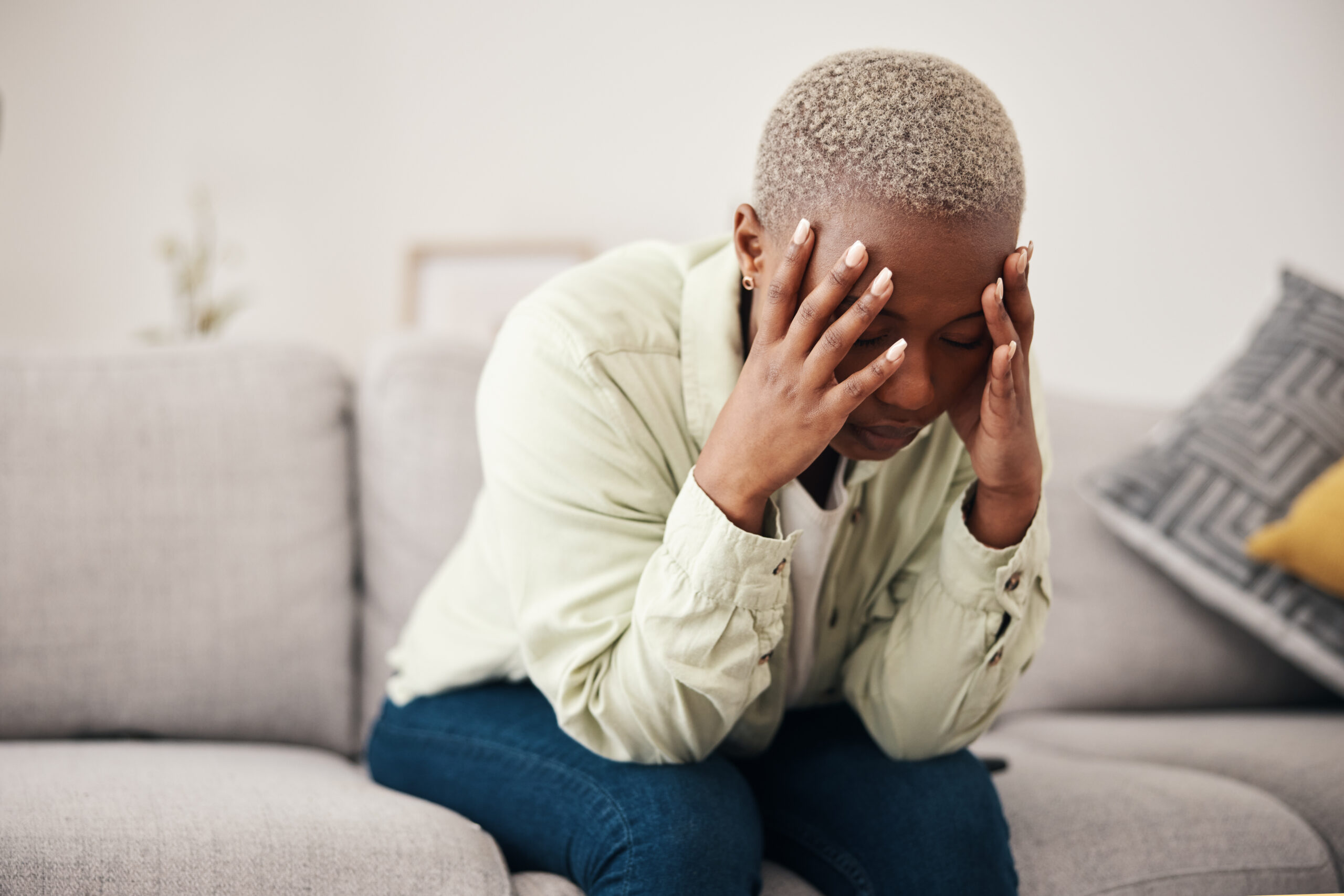 Stress, headache and vertigo with a black woman on a sofa in the living room of her home for mental.